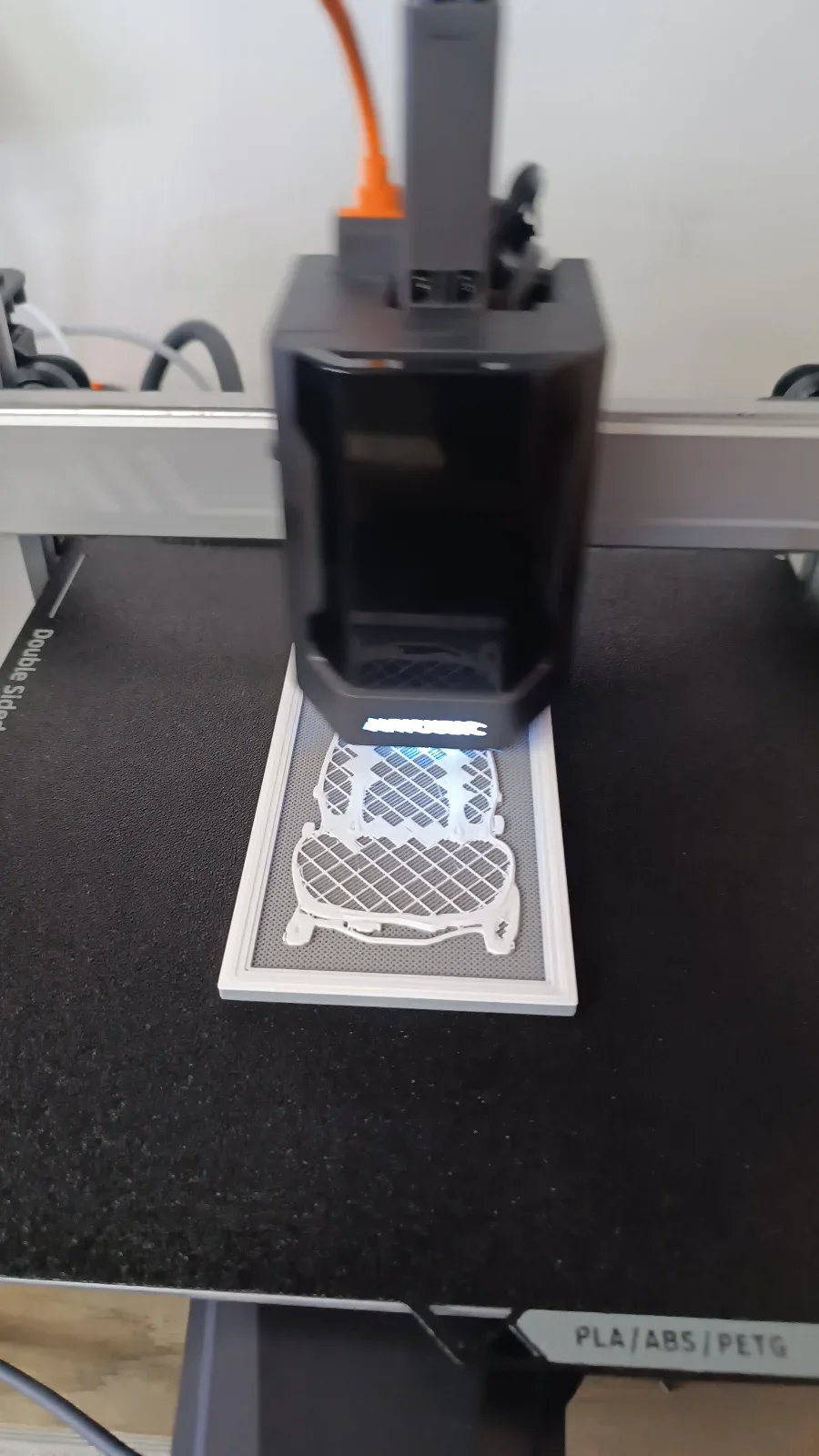 3D-принтер печатает белые заготовки в форме спинки и подушки автосиденья